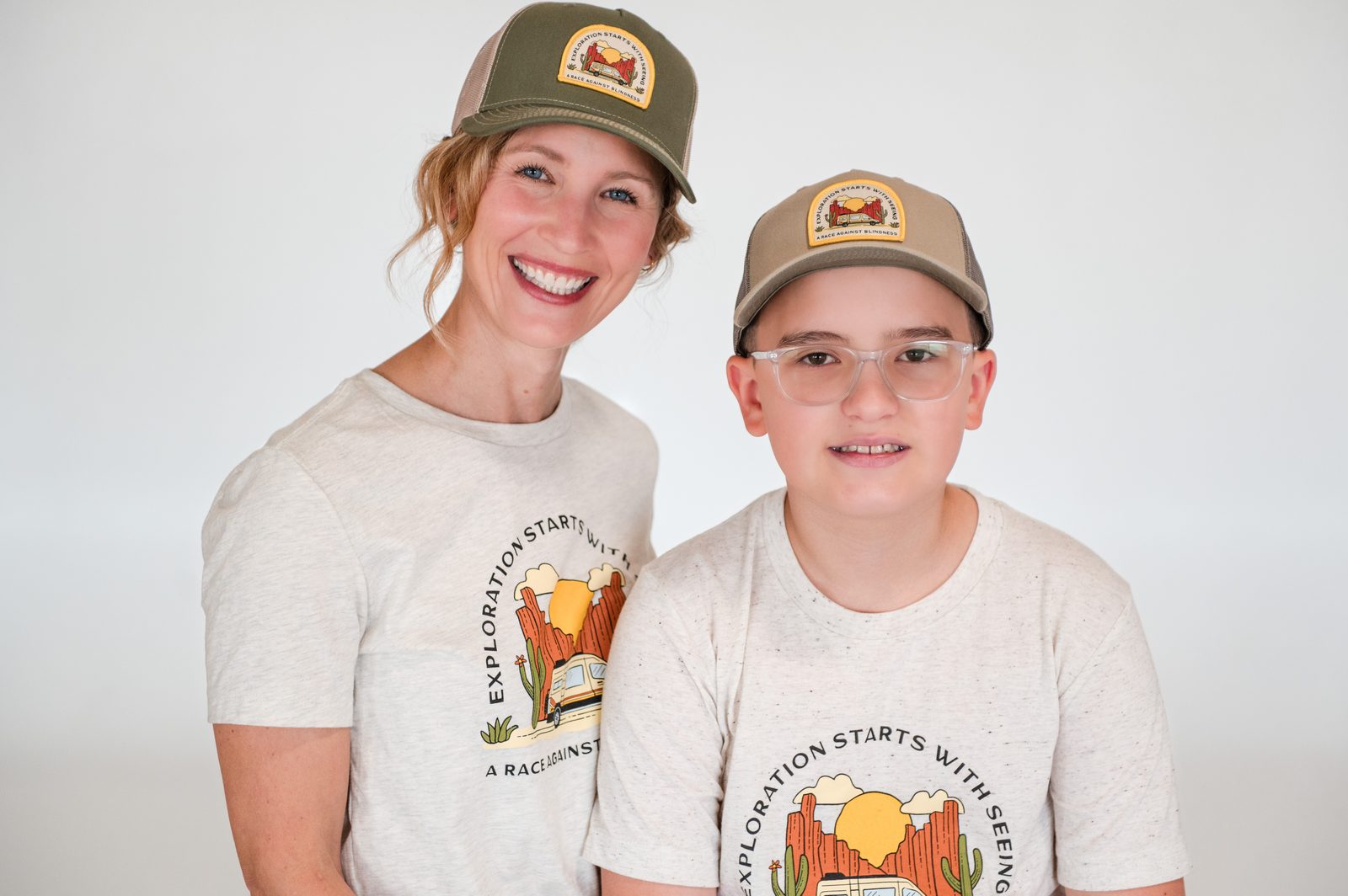A mother and son in matching caps and RAB shirts smile side by side.
